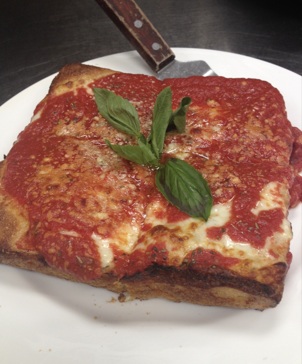 Square pizza with tomato sauce, cheese, and fresh basil